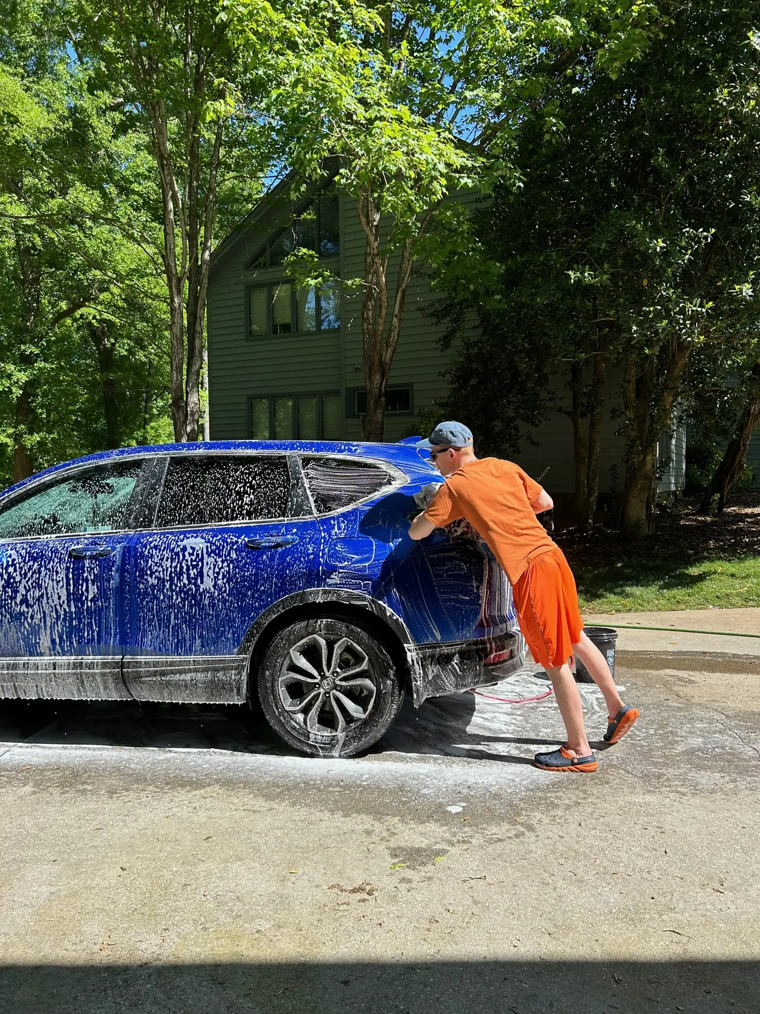 Alexander hand washing a blue SUV during a detailing appointment